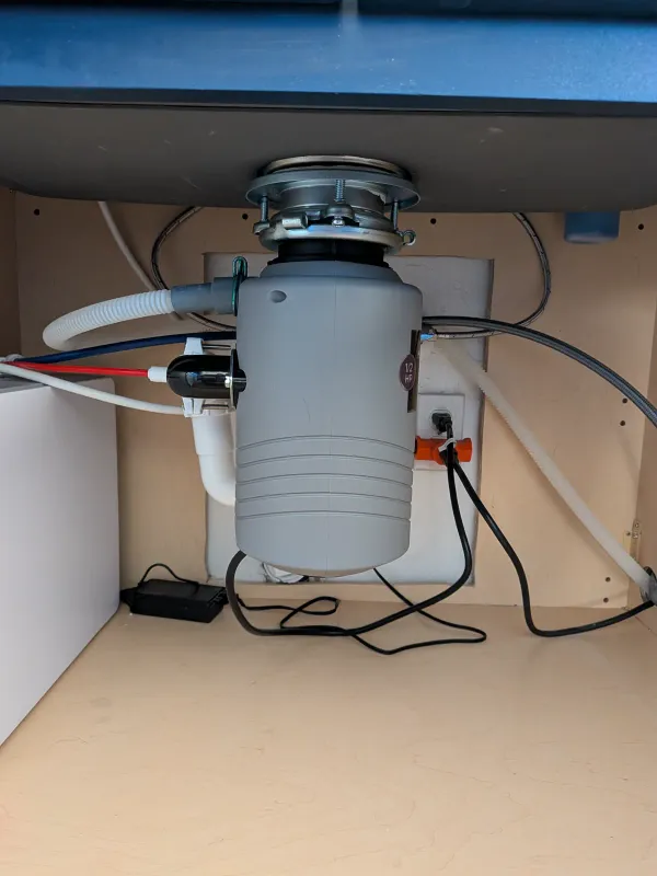 Close view of the installed garbage disposal connected below the kitchen sink